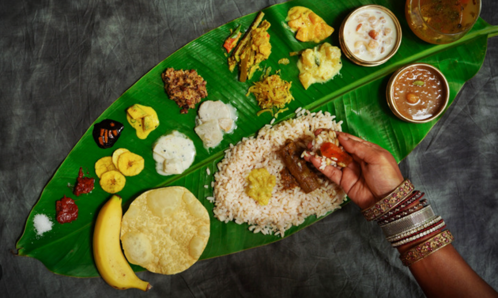 indian lady eating a traditional banana leaf rice meal with her hands